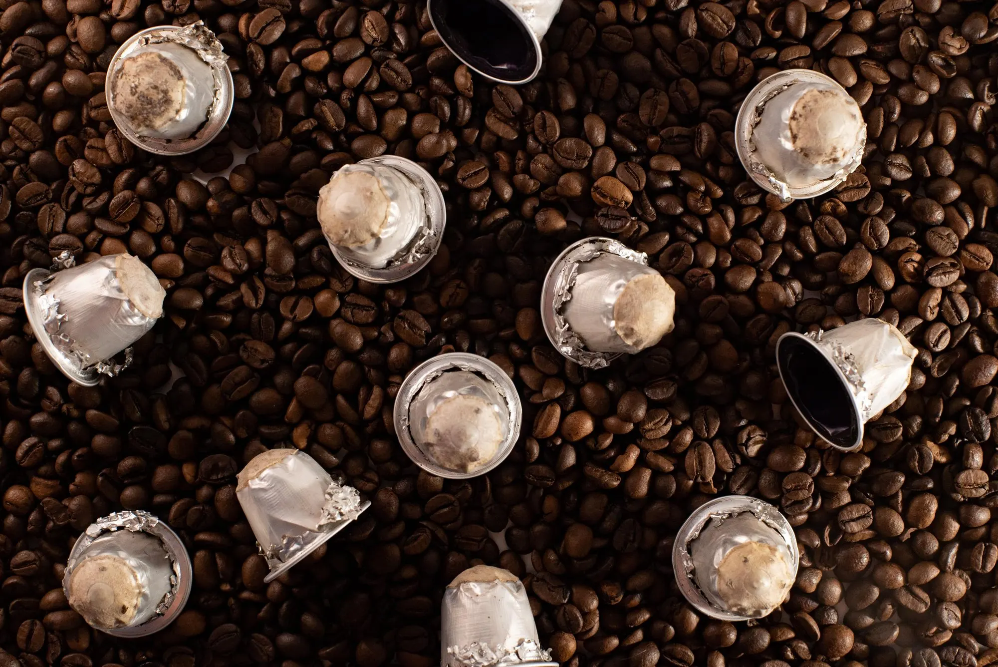 Capsule di caffè usate sparse su chicchi di caffè