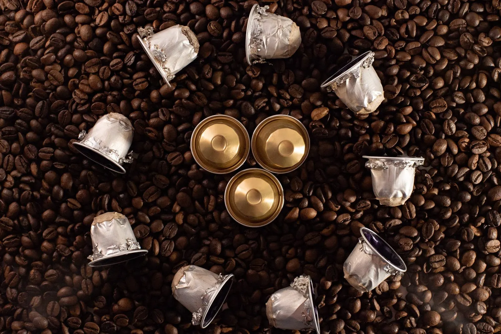 Capsule di caffè usate sparse su chicchi di caffè