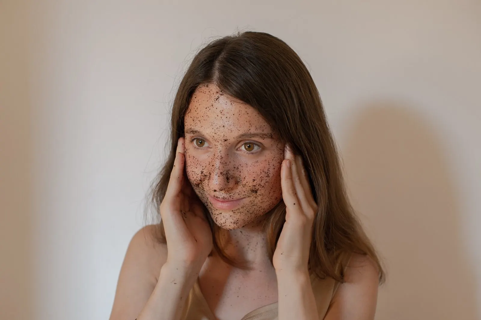 Una ragazza con una maschera di fondi di caffè sul viso