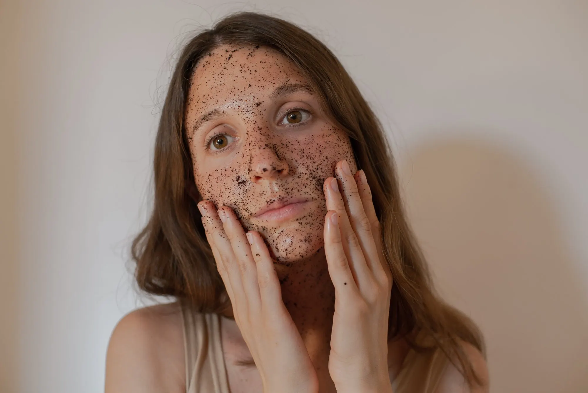 Una ragazza con una maschera di fondi di caffè sul viso